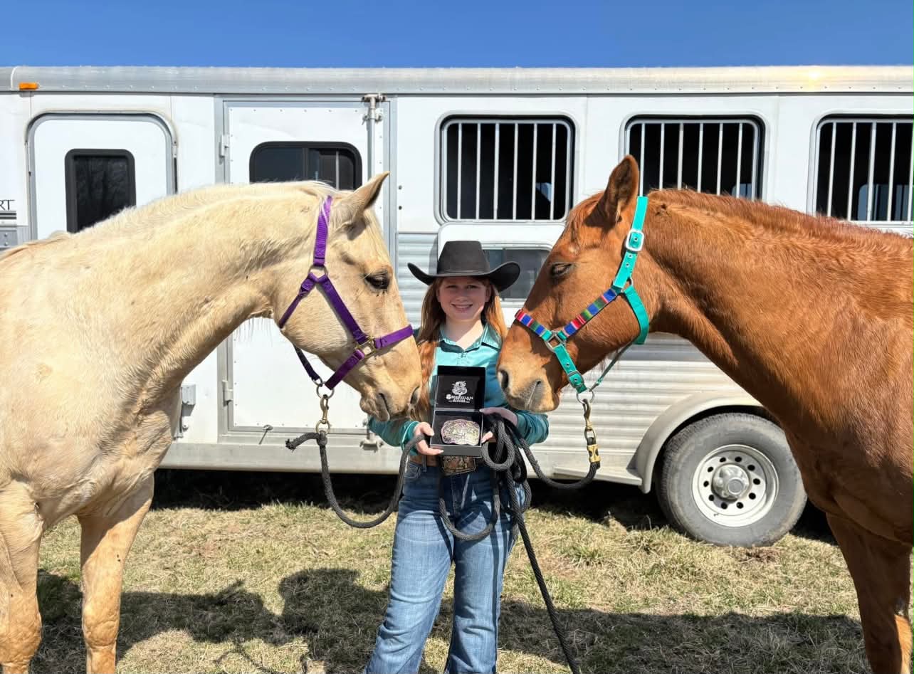 Macy Jennings holding her champion buckle between Cinch and Bug